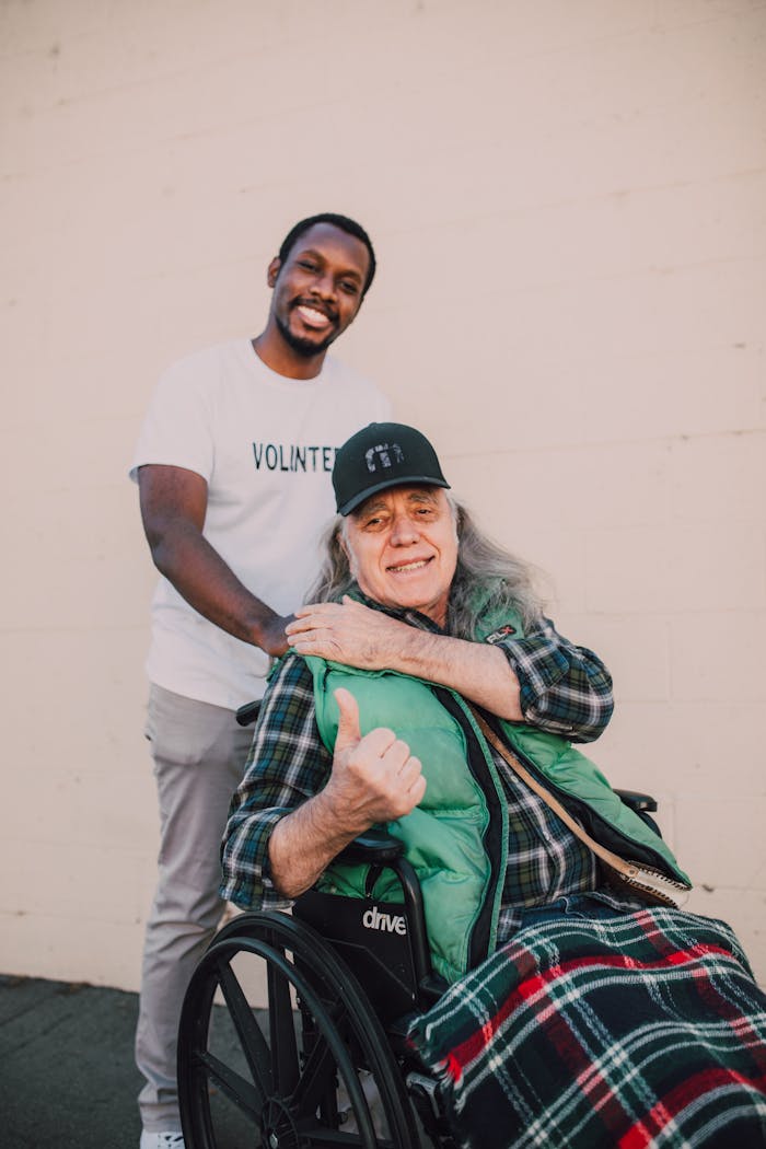 Happy volunteer with elderly man in wheelchair, showcasing kindness and community support.